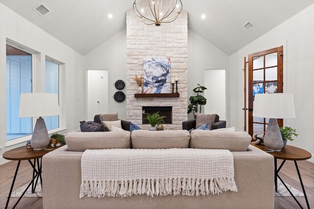 living room featuring wood-type flooring, a fireplace, a chandelier, and vaulted ceiling