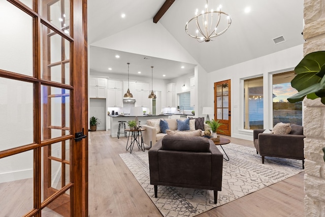 living room with beamed ceiling, high vaulted ceiling, light hardwood / wood-style flooring, and a notable chandelier