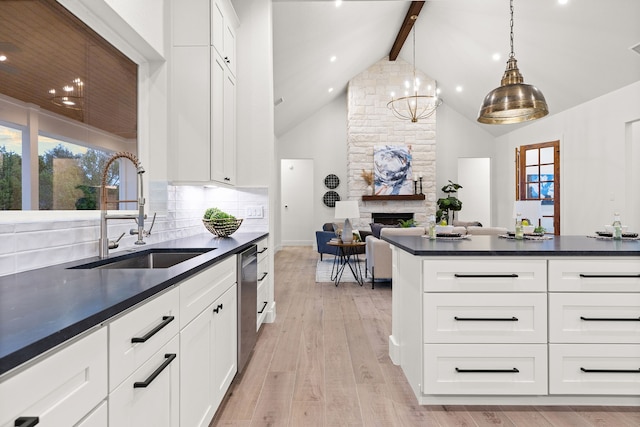 kitchen with white cabinetry, sink, backsplash, and decorative light fixtures