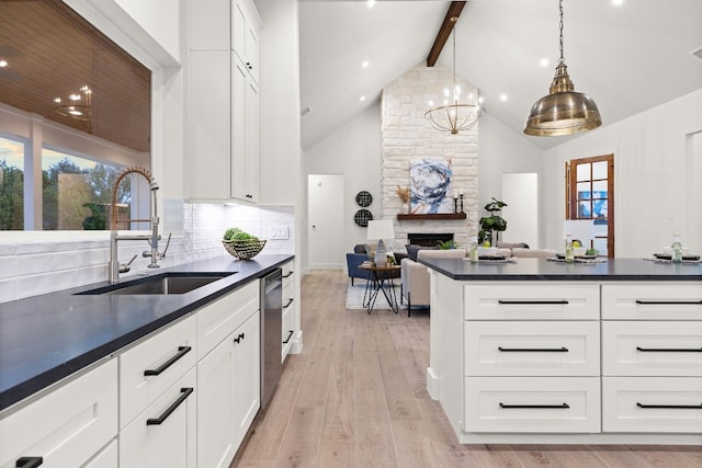 kitchen with white cabinetry, sink, hanging light fixtures, stainless steel dishwasher, and beam ceiling