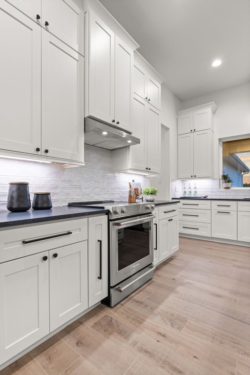 kitchen with electric stove, white cabinetry, tasteful backsplash, and light hardwood / wood-style flooring