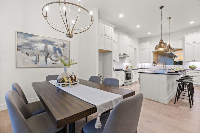 dining room featuring sink, a chandelier, and light hardwood / wood-style flooring