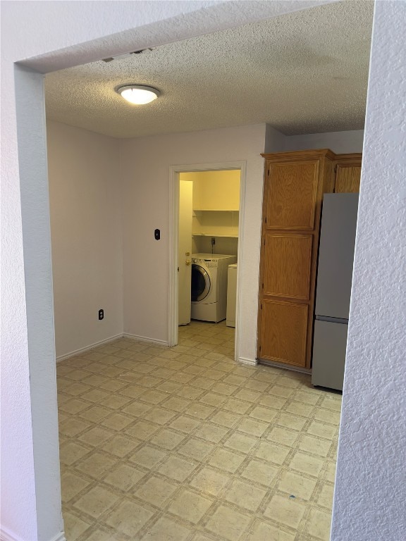 kitchen featuring stainless steel refrigerator, independent washer and dryer, a textured ceiling, and light tile floors