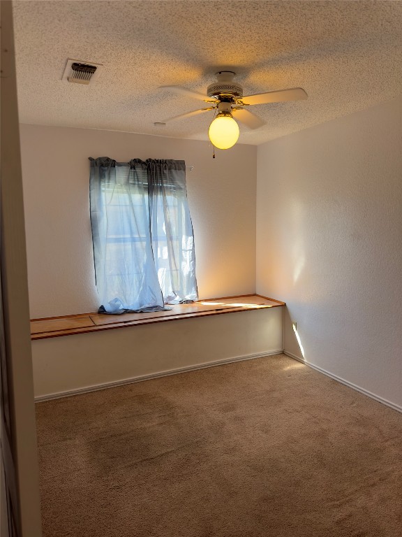 spare room with carpet flooring, ceiling fan, and a textured ceiling