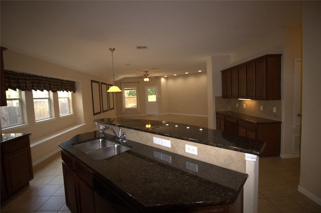 kitchen featuring backsplash, a kitchen island with sink, ceiling fan, and sink