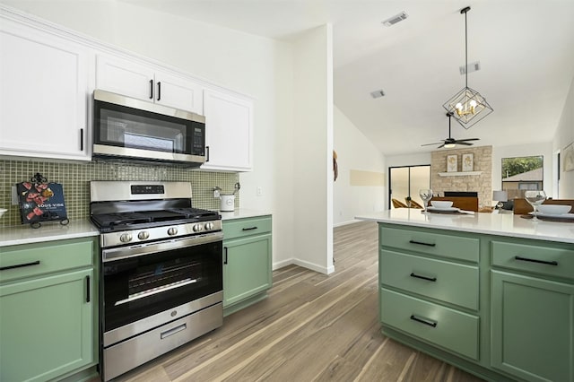 kitchen with decorative backsplash, a fireplace, stainless steel appliances, dark wood-type flooring, and white cabinets