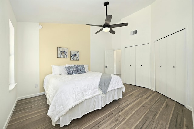 bedroom with multiple closets, ceiling fan, high vaulted ceiling, and dark hardwood / wood-style floors