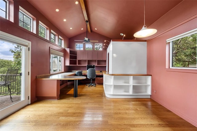 unfurnished office featuring plenty of natural light, built in desk, and light hardwood / wood-style flooring