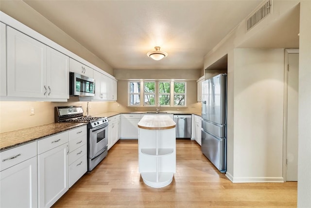 kitchen featuring sink, a center island, light hardwood / wood-style flooring, stainless steel appliances, and white cabinets