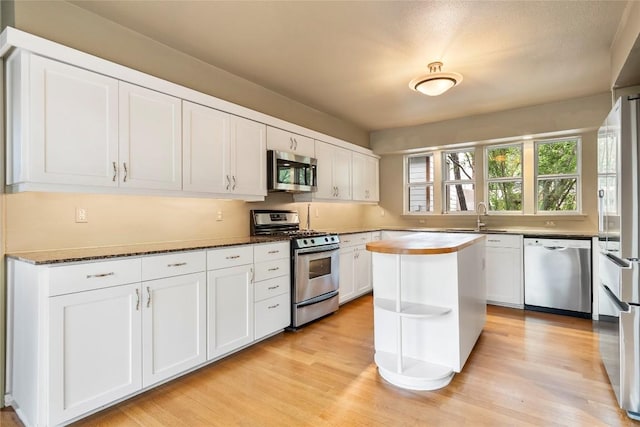 kitchen featuring light wood finished floors, white cabinetry, stainless steel appliances, and a sink