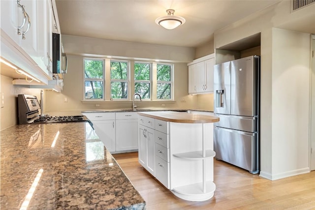 kitchen with stainless steel appliances, visible vents, white cabinets, a sink, and butcher block countertops