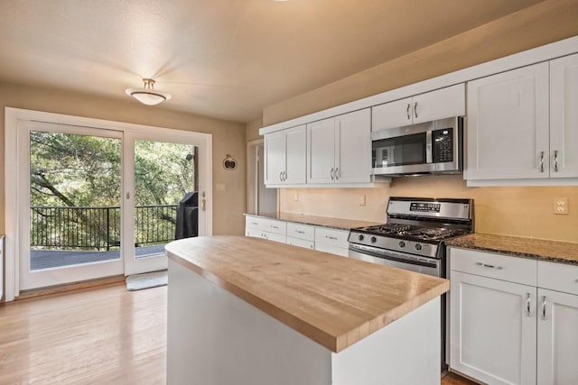 kitchen featuring white cabinetry, butcher block countertops, appliances with stainless steel finishes, and a center island