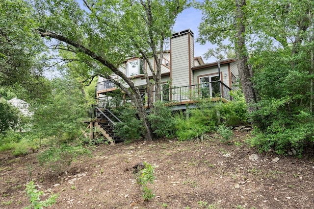 rear view of house with stairway, a chimney, and a deck