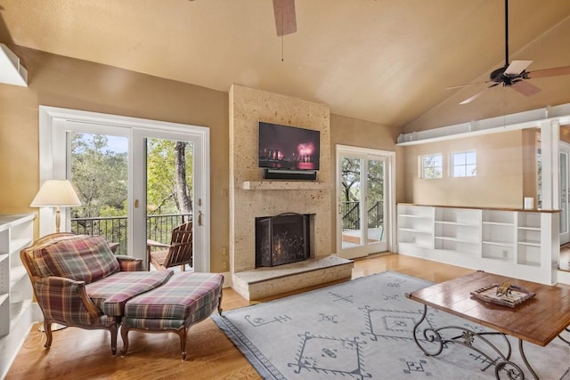 living room with lofted ceiling, a large fireplace, hardwood / wood-style floors, and ceiling fan