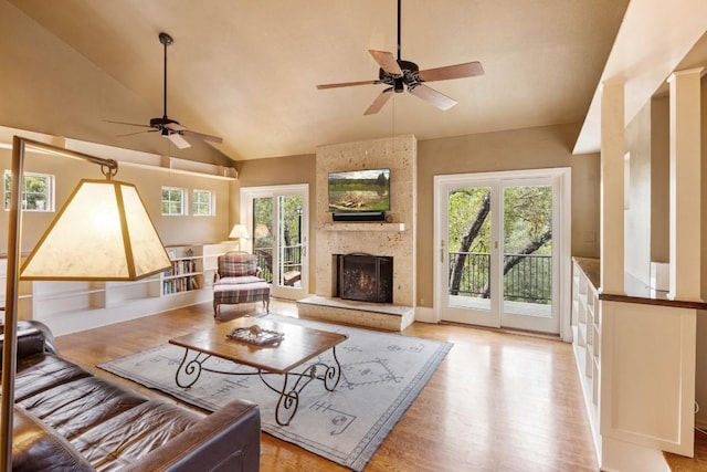 living area featuring lofted ceiling, a fireplace, light wood-style flooring, and ceiling fan