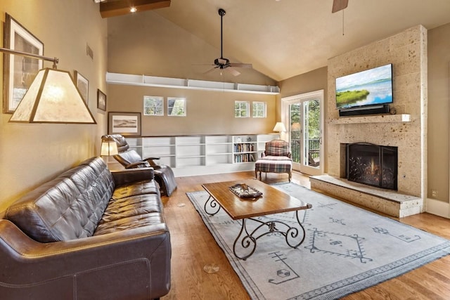 living room with hardwood / wood-style floors, high vaulted ceiling, a large fireplace, and ceiling fan