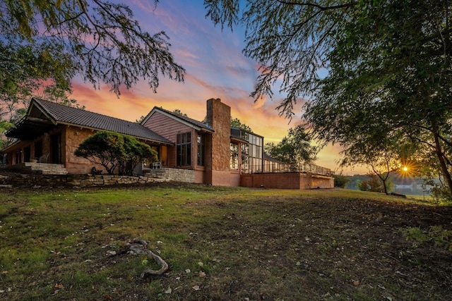 property exterior at dusk featuring a lawn