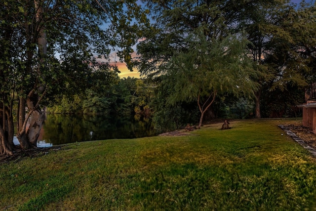 yard at dusk featuring a water view