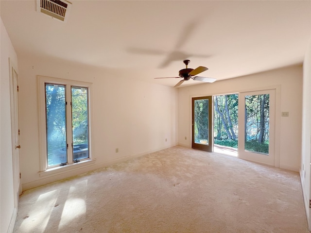 carpeted spare room featuring ceiling fan and a wealth of natural light