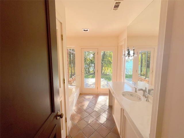 bathroom featuring a washtub, vanity, tile patterned flooring, and a chandelier