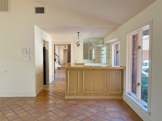 kitchen featuring a wealth of natural light, light brown cabinets, decorative light fixtures, and vaulted ceiling