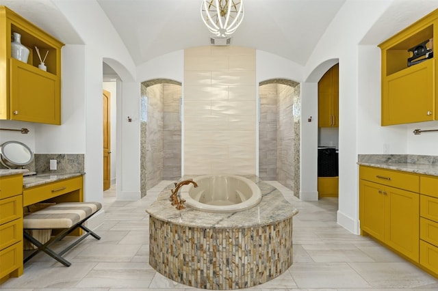 bathroom featuring vanity, lofted ceiling, and tiled tub