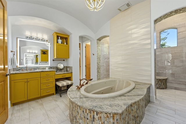 bathroom with vanity, a relaxing tiled tub, and lofted ceiling