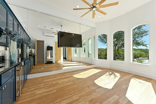 unfurnished sunroom featuring an AC wall unit, ceiling fan, and a healthy amount of sunlight