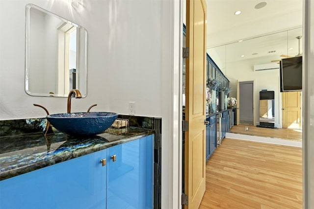 bathroom featuring vanity, hardwood / wood-style flooring, and a wall unit AC