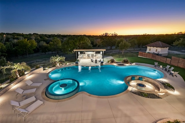 pool at dusk with an in ground hot tub and a patio