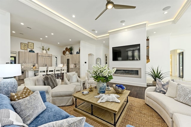 living room featuring dark hardwood / wood-style floors, ceiling fan, and crown molding