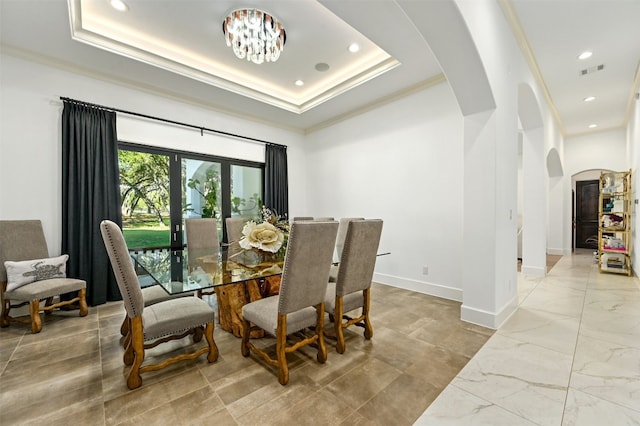 dining space with a raised ceiling, crown molding, and an inviting chandelier