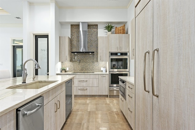 kitchen featuring sink, wall chimney range hood, tasteful backsplash, light brown cabinetry, and black appliances