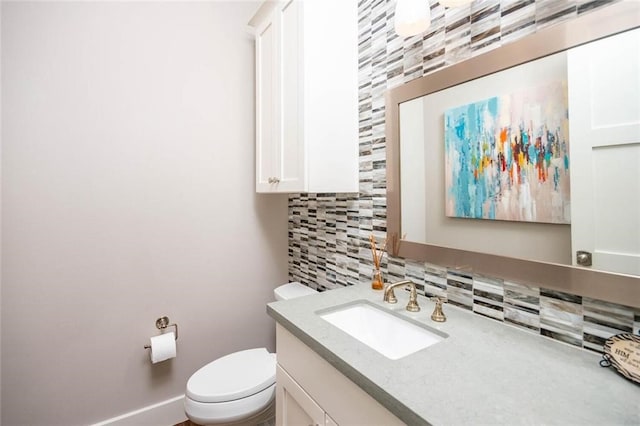 half bathroom with tasteful backsplash, toilet, vanity, and baseboards