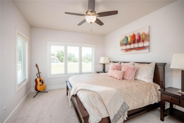 bedroom featuring a ceiling fan, light colored carpet, and baseboards