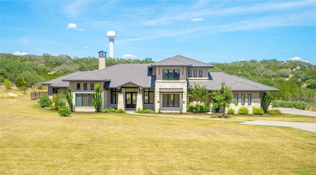 prairie-style home with a front lawn, a tiled roof, and stone siding