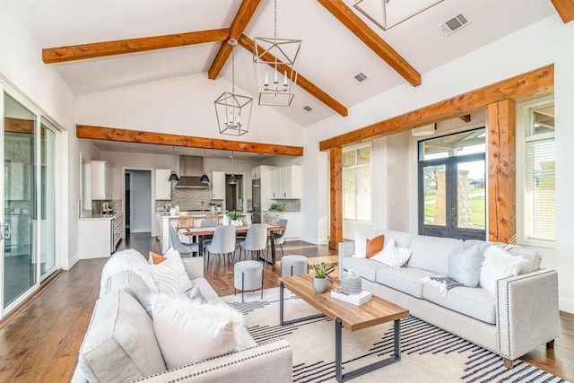 living area with visible vents, a notable chandelier, beamed ceiling, and hardwood / wood-style floors