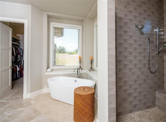 bathroom with a walk in closet, a freestanding tub, a walk in shower, and baseboards