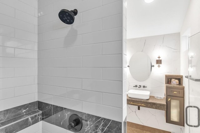 bathroom featuring a shower with door and sink