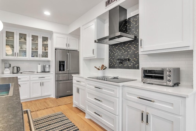 kitchen with black electric stovetop, wall chimney exhaust hood, white cabinetry, and high end refrigerator