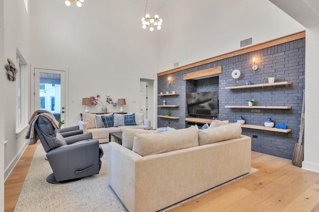 living room with a chandelier, a high ceiling, light hardwood / wood-style floors, and built in shelves