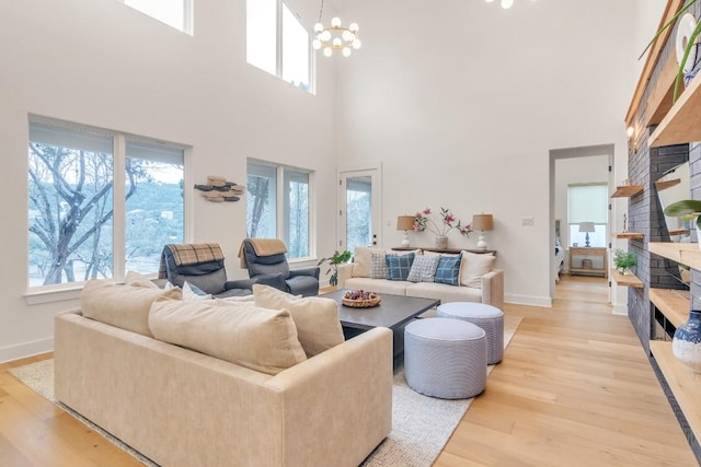 living room featuring light hardwood / wood-style floors, a towering ceiling, and an inviting chandelier