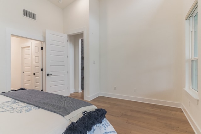 bedroom with hardwood / wood-style floors, a towering ceiling, and a closet