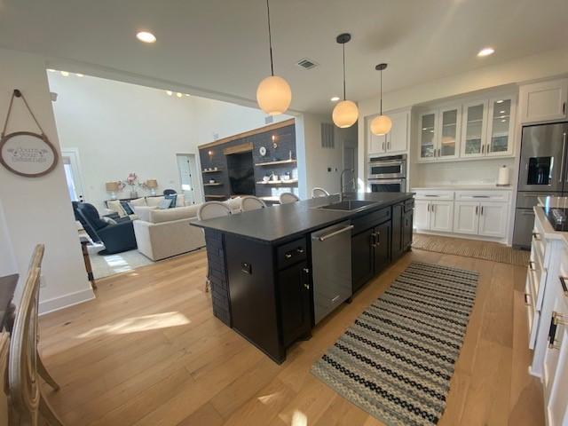 kitchen featuring sink, white cabinets, stainless steel appliances, and decorative light fixtures