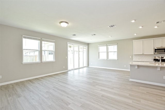 unfurnished living room featuring sink and light wood-type flooring