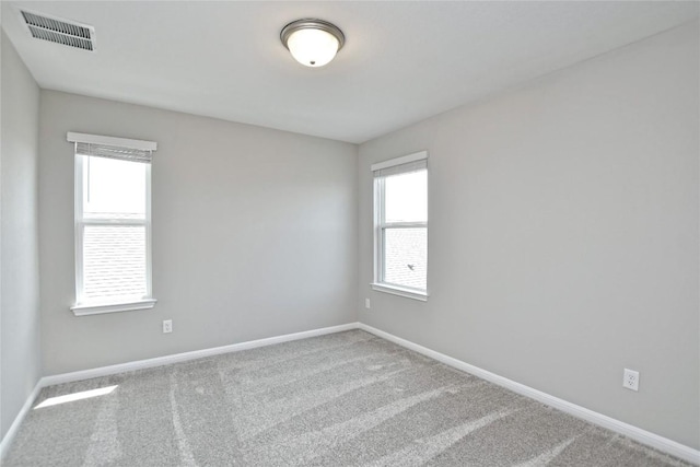 carpeted spare room with visible vents and baseboards