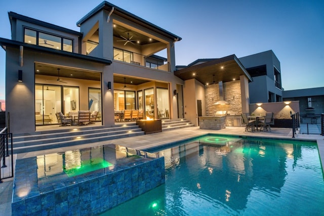 pool at dusk featuring an outdoor living space, ceiling fan, and a patio area