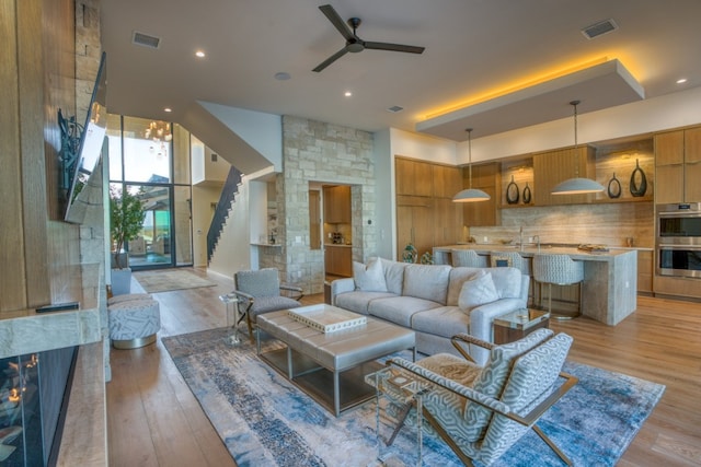 living room featuring light hardwood / wood-style flooring, ceiling fan, and sink