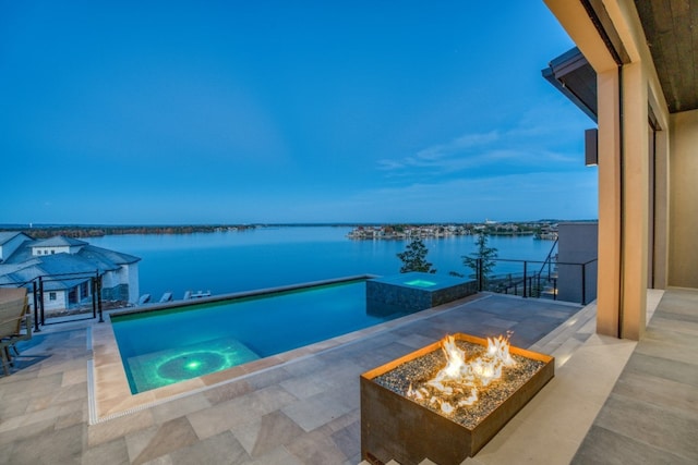 pool at dusk with a water view, an in ground hot tub, a fire pit, a gazebo, and a patio area