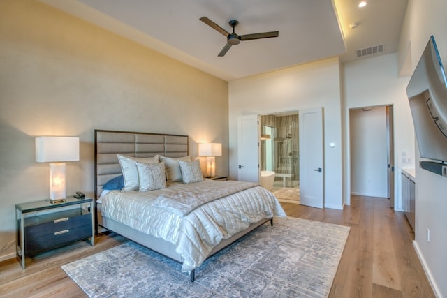 bedroom with a high ceiling, light hardwood / wood-style floors, ceiling fan, and ensuite bathroom